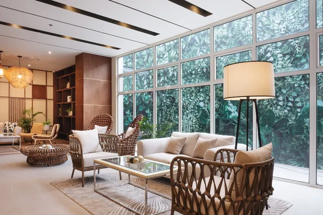 The lobby lounge, with rattan chairs and a wall of glass onto planting